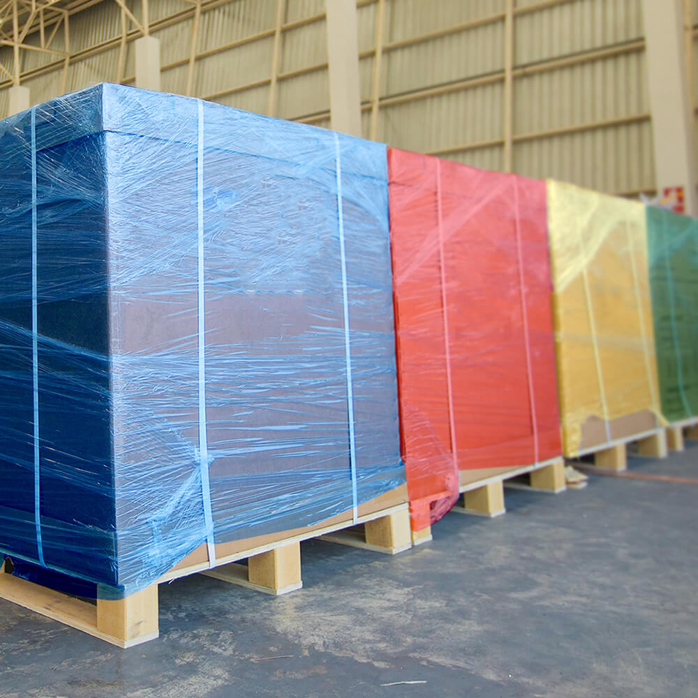 large warehouse pallets wrapped in solid colored shrink wrap, blue, red, yellow, and green