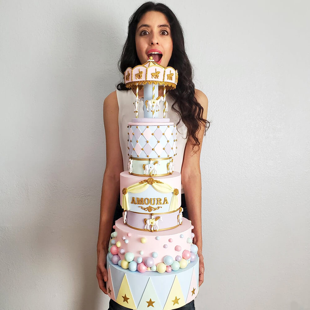 Owner and founder of Smashing Cake Toppers, Analy Garcia holding a beautifully decorated fake cake