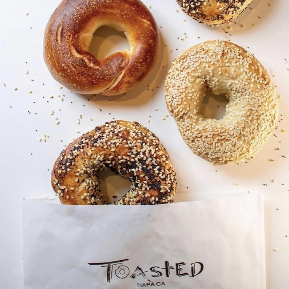 Flat lay image of Toasted Napa bagels next to Paper Mart bags